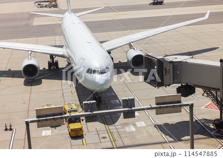 Airplane at gate with boarding passengers and ground crew 114547885