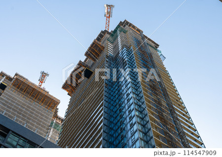 Upward view of modern skyscraper against blue sky 114547909