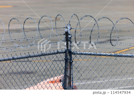 Security barbed wire on airport perimeter fence 114547934