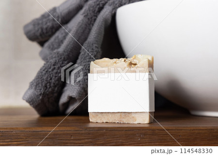 Soap bar with blank label near grey towel on basin on wooden countertop in bath, mockup Soap bar with blank label near grey towel on basin on wooden countertop in bath, mockup 114548330