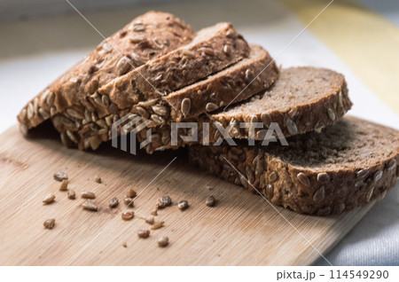 Sliced rye bread with sunflower seeds on wooden cutting board 114549290