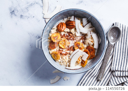 Overnight oatmeal with chocolate, pecans, coconut chips and dried banana, white background. 114550726