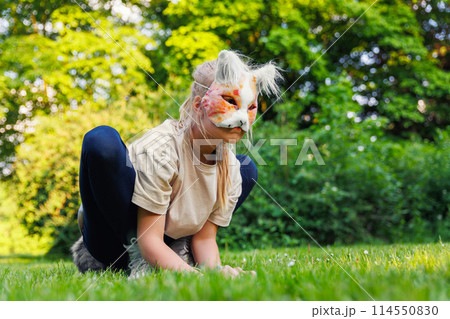 Cute young little kid girl wear cat furry mask enjoy have fun playing outdoors in forest street park. Children therian wild animal character trendy fan culture. Teenager social expression hobby 114550830