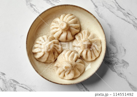 Savory khinkali dumplings sprinkled with black pepper on ceramic bowl Savory khinkali dumplings sprinkled with black pepper on ceramic bowl 114551492