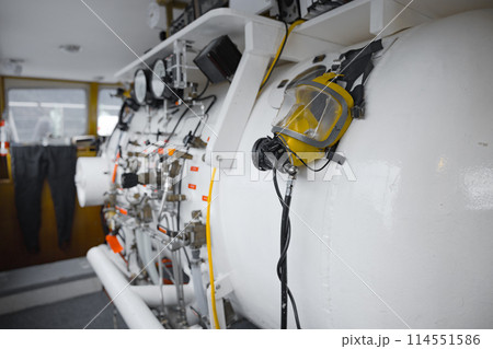 Side view of hyperbaric chamber with valves and pipes 114551586
