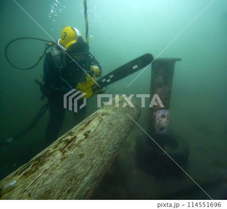 Commercial diver cutting log underwater with chainsaw Commercial diver cutting log underwater with chainsaw 114551696