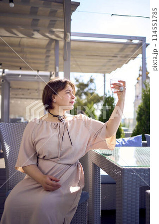medium sized woman in peach fuzz dress with glass of water in restaurant medium sized woman in peach fuzz dress with glass of water in restaurant 114551785