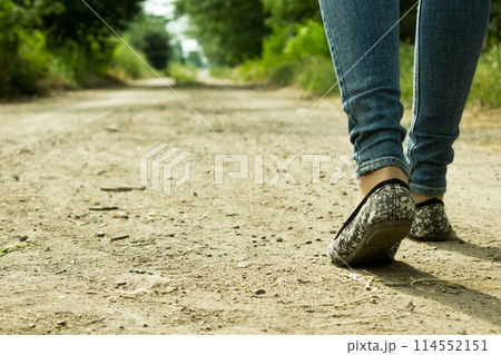 The girl goes on a dirt road through the trees 114552151