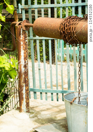 Well water and a bucket on a chain 114552180