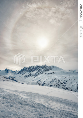 Sun halo over snowy mountains in the French Alps 114552402