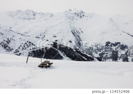 Wooden bench on a snowy hillside in the French Alps 114552406