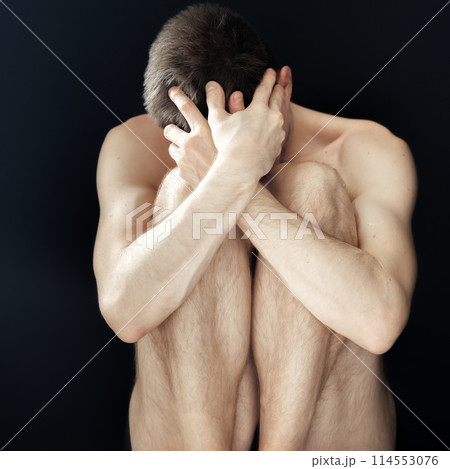 Man sitting in fear covering his face 114553076