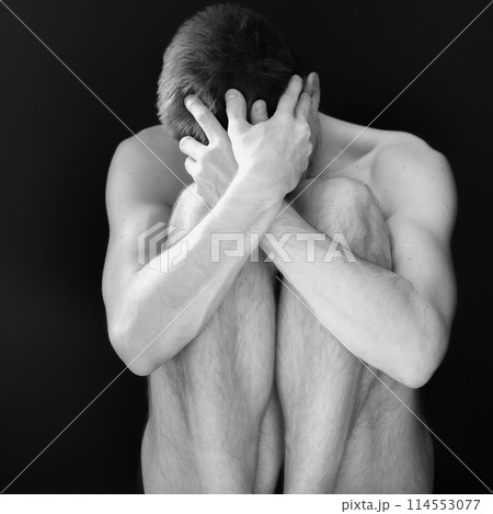 Man sitting in fear covering his face 114553077