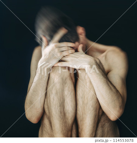 Man sitting in fear covering his face 114553078