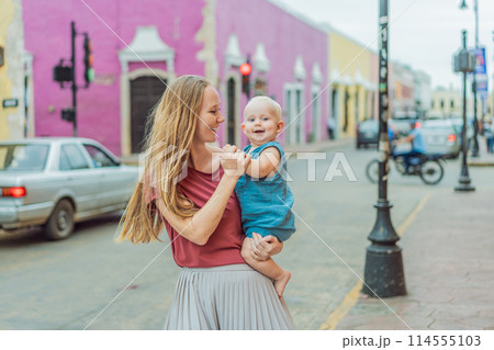 Mother and baby son tourists explore the vibrant streets of Valladolid, Mexico, immersing herself in the rich culture and colorful architecture of this charming colonial town 114555103