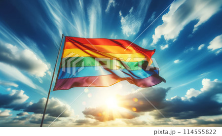 Rainbow flag waving in sky, illuminated by sunlight, symbolizing freedom, pride, LGBTQ community 114555822
