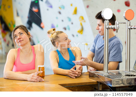 Two sports women and a guy communicate after training on a climbing wall at a table in cafe 114557049