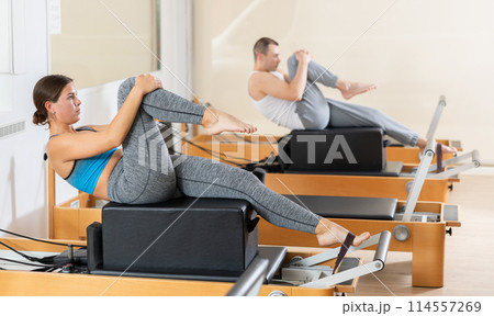 Female athletic girl doing stretching on pilates machine in pilates studio Female athletic girl doing stretching on pilates machine in pilates studio 114557269