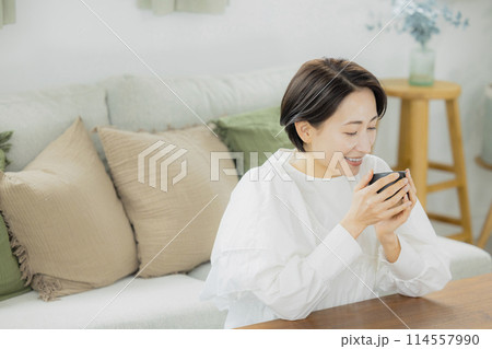 リビングでコーヒーを飲むミドル女性　 114557990