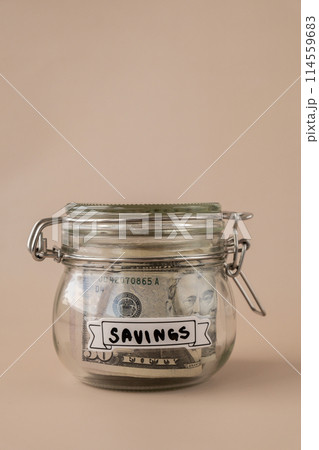 Glass jar full of American currency dollars cash banknote with text SAVINGS. Preparation saving money. Moderate consumption and economy 114559683