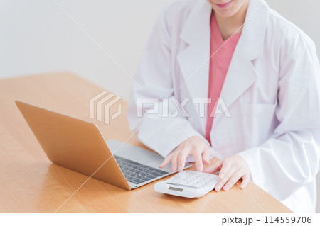 電卓で計算する女性医師 114559706