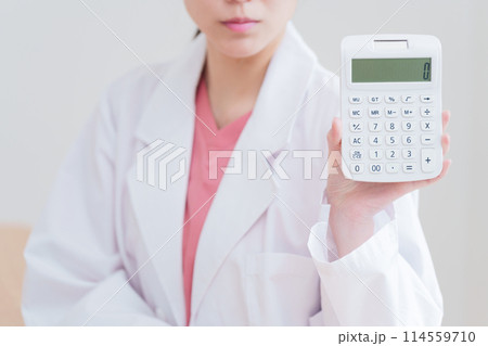 電卓で計算する女性医師 電卓で計算する女性医師 114559710