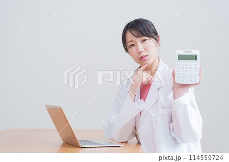 電卓で計算する考える女性医師 電卓で計算する考える女性医師 114559724