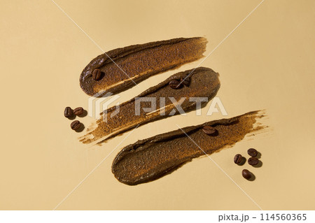 Creative design template with dark brown exfoliation smudges has coffee origin decorated against light brown flat, coffee beans scattered around. Copy space for text, high angle shot 114560365