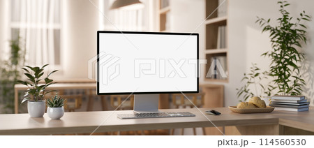 A computer mockup and objects are on a wooden table in a contemporary minimalist co-working space. 114560530