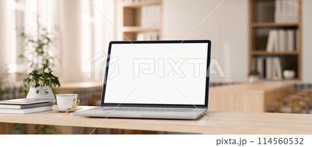 A laptop computer mockup on a wooden tabletop in a contemporary minimalist cafe co-working space. 114560532