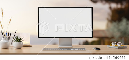A PC computer mockup and accessories on a wooden desk with a blurred background of an outdoors. A PC computer mockup and accessories on a wooden desk with a blurred background of an outdoors. 114560651