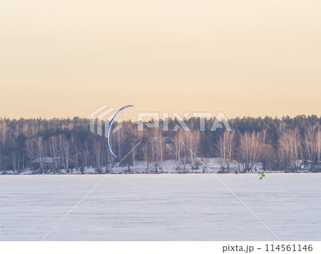 Kite surfer ride on snowboard. Snowkiting in the snow on frozen lake. 114561146