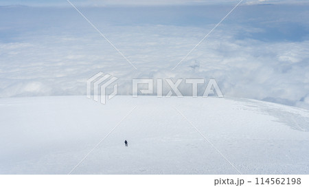 Solo mountaineer walking big glacier field above the clouds, Mount Ararat in Turkey 114562198