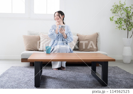 綺麗なリビングでスマホを持って考える若い女性 綺麗なリビングでスマホを持って考える若い女性 114562525