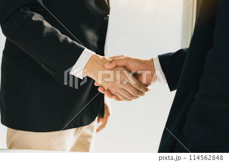 Business people in office suits standing and shaking hands, close-up. Business communication concept. Handshake and marketing. 114562848