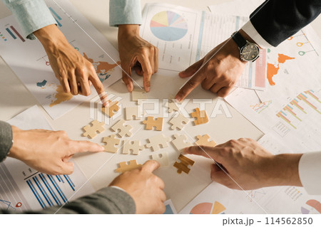 The concept of teamwork and partnership. Businessman's hands putting together puzzle pieces in the office and join together in a jigsaw puzzle team. Charity. Volunteers. Business unity as a team. 114562850