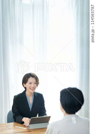 私服の女性に説明するスーツ姿の女性 114563787