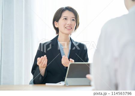 私服の女性に説明するスーツ姿の女性 私服の女性に説明するスーツ姿の女性 114563796