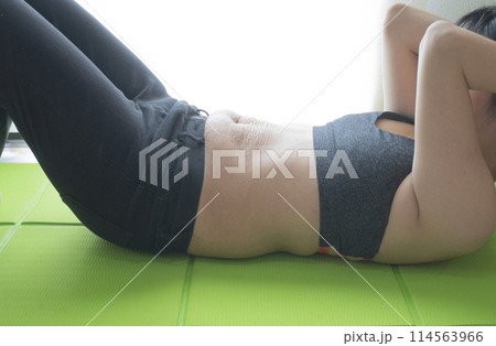 産後の妊娠線が残るお腹で腹筋運動をする女性 114563966
