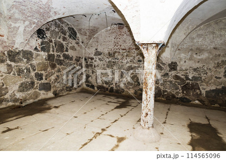 A room with stone walls, a white pillar, and an archway 114565096