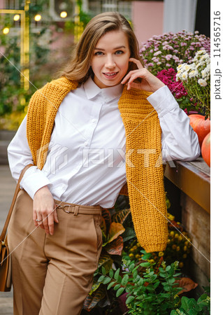 Portrait of lovely woman at an autumn fair leaning on a wooden display table Portrait of lovely woman at an autumn fair leaning on a wooden display table 114565716