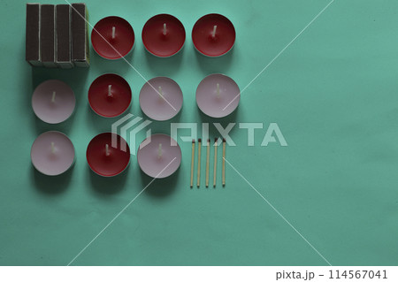 Decorative candles, matchboxes and matches are arranged in a row. On a mint background. Decorative candles, matchboxes and matches are arranged in a row. On a mint background. 114567041