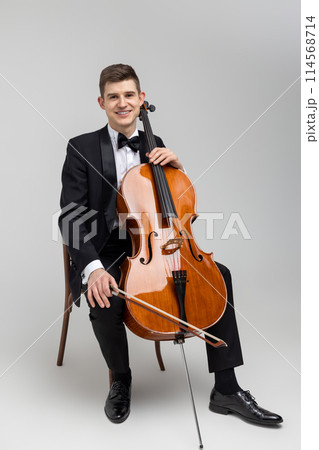 Young male artist sitting on chair and playing contrabass 114568714