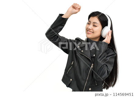 ヘッドホンで音楽を聴いて盛り上がる革ジャンを着た若い女性 114569451