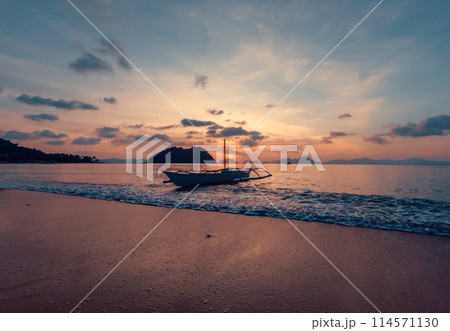 Stunning sunset over serene beach with boat in calm waters, evening time. Stunning sunset over serene beach with boat in calm waters, evening time. 114571130