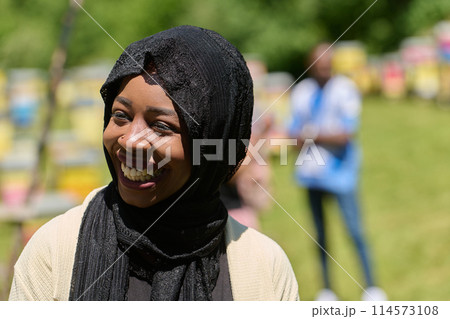 Joyful Middle Eastern Muslim Woman in Hijab Smiling Brightly in a Natural Apiary 114573108