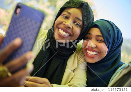 Middle Eastern Muslim Women Capturing Selfies in Serene Surroundings 114573121