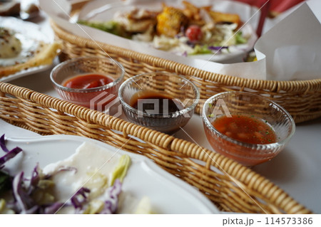 Restaurant food in a wicker basket with sauces on the table 114573386