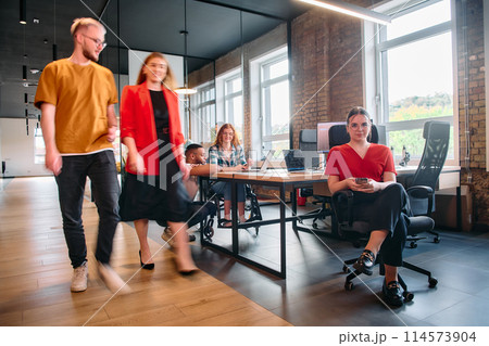 A diverse group of business professionals collaborates in a modern startup coworking center, utilizing a mix of paper-based and technological tools such as mobile phones and computers A diverse group of business professionals collaborates in a modern startup coworking center, utilizing a mix of paper-based and technological tools such as mobile phones and computers 114573904