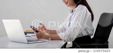 Asian Businesswoman Using Smartphone and Laptop in Office 114575025